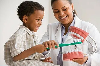 Dentist show to a boy how to brush a teeth