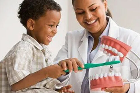 Dentist show to a boy how to brush a teeth